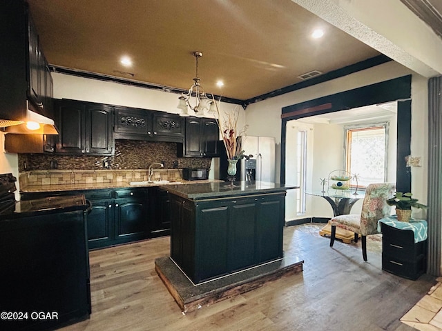 kitchen with sink, black electric range, crown molding, a kitchen island, and light wood-type flooring