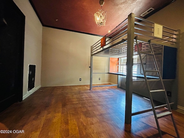 interior space featuring a chandelier, wood-type flooring, ornamental molding, and a textured ceiling