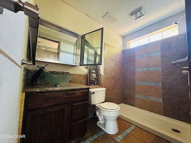 bathroom featuring tiled shower, toilet, tile patterned floors, a textured ceiling, and vanity