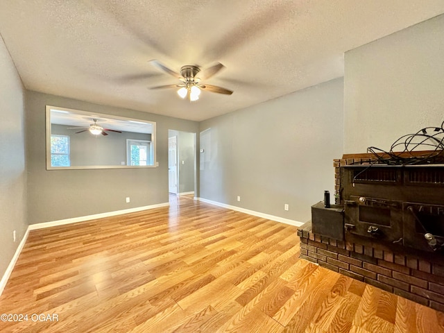 living room with light hardwood / wood-style flooring, a textured ceiling, and ceiling fan