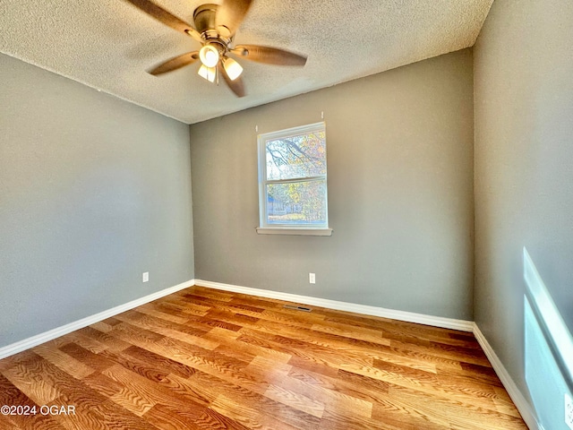 empty room with a textured ceiling, light wood-type flooring, and ceiling fan