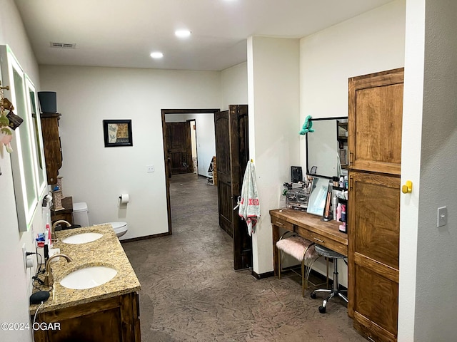 bathroom featuring double vanity, a sink, toilet, and baseboards