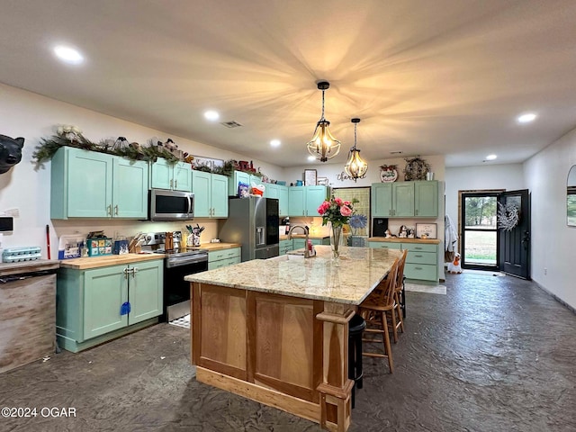 kitchen with a kitchen breakfast bar, decorative light fixtures, a kitchen island with sink, stainless steel appliances, and a sink