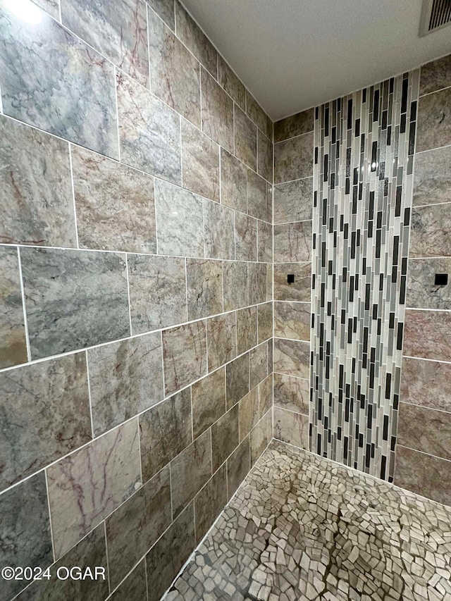 full bath featuring tiled shower and visible vents