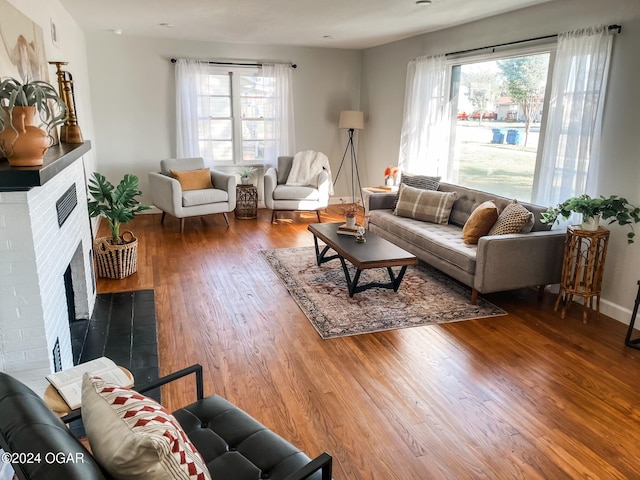 living room with a wealth of natural light, a fireplace, and wood-type flooring