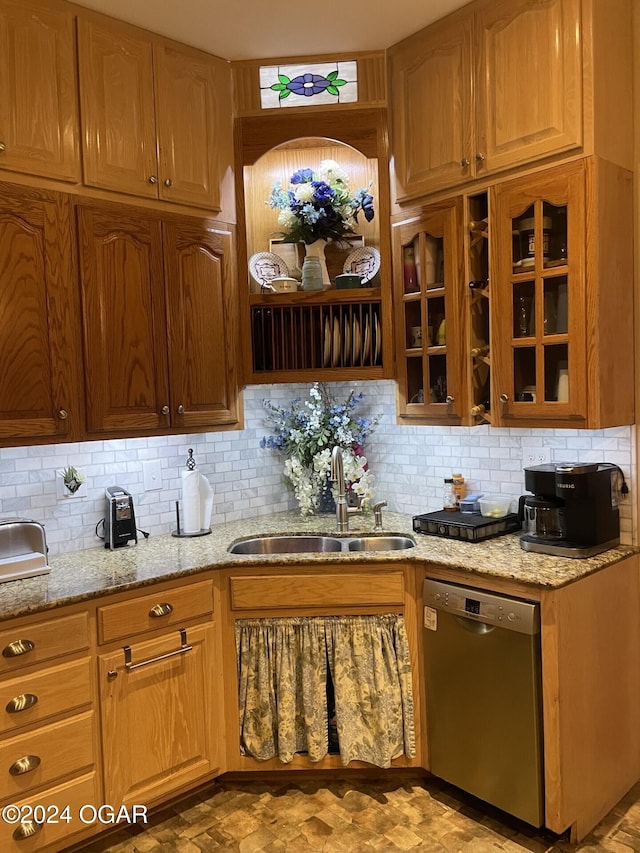 kitchen featuring stainless steel dishwasher, light stone countertops, sink, and tasteful backsplash