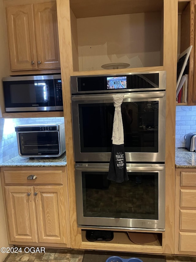 kitchen with light stone countertops, decorative backsplash, and appliances with stainless steel finishes