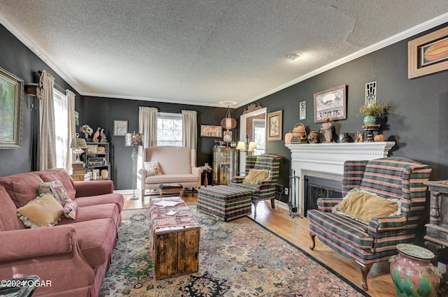 living room featuring a textured ceiling, a fireplace, wood finished floors, baseboards, and ornamental molding