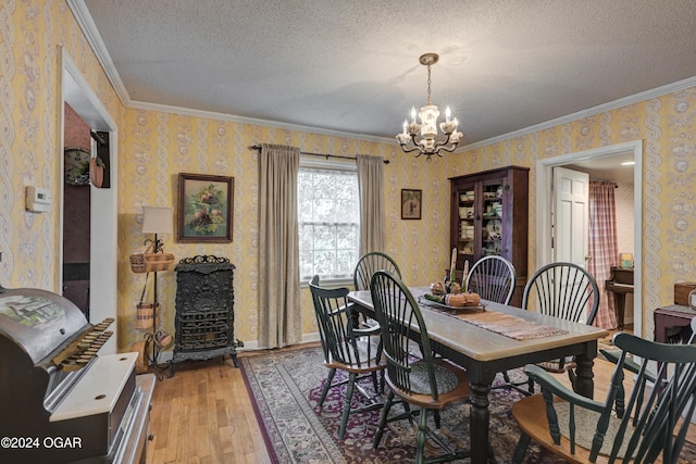 dining room featuring light wood-style flooring, a textured ceiling, an inviting chandelier, and wallpapered walls