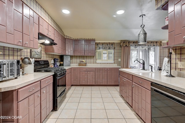 kitchen with decorative light fixtures, light countertops, a sink, under cabinet range hood, and black appliances