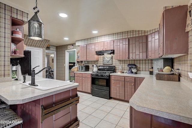 kitchen with black range with gas cooktop, decorative light fixtures, a peninsula, light countertops, and under cabinet range hood