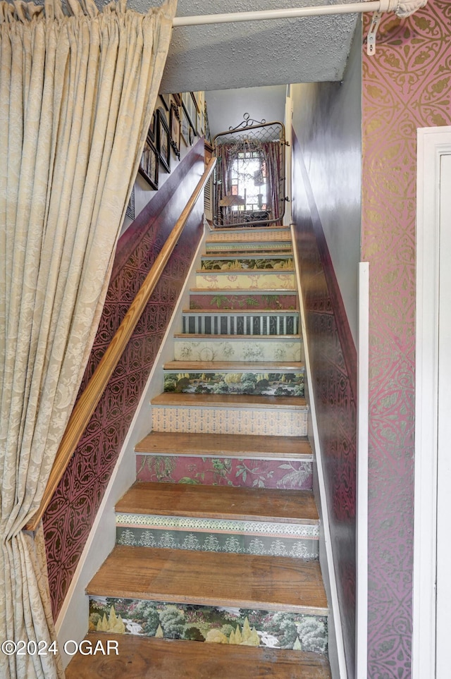 staircase with wallpapered walls and baseboards