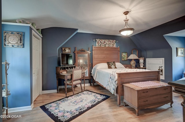 bedroom featuring lofted ceiling, light wood finished floors, and baseboards