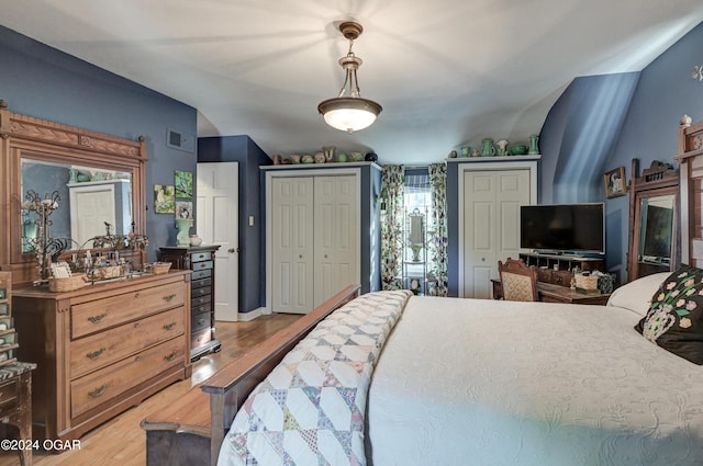 bedroom featuring multiple closets, visible vents, and light wood-style floors