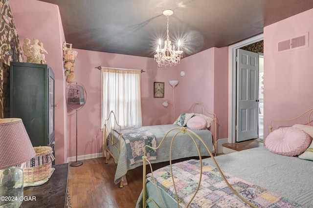 bedroom with visible vents, a notable chandelier, baseboards, and wood finished floors