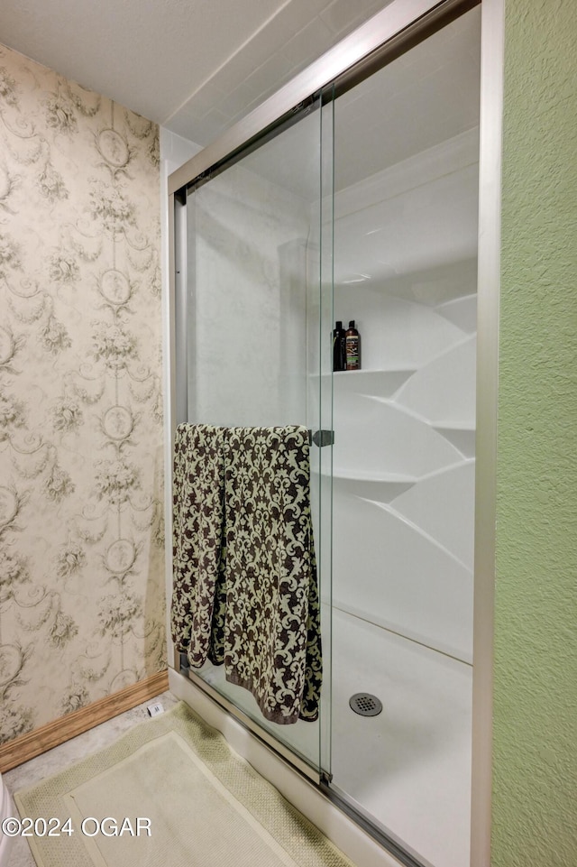 bathroom with a shower stall and wallpapered walls