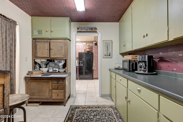 kitchen featuring light tile patterned floors, dark countertops, an ornate ceiling, black appliances, and green cabinetry