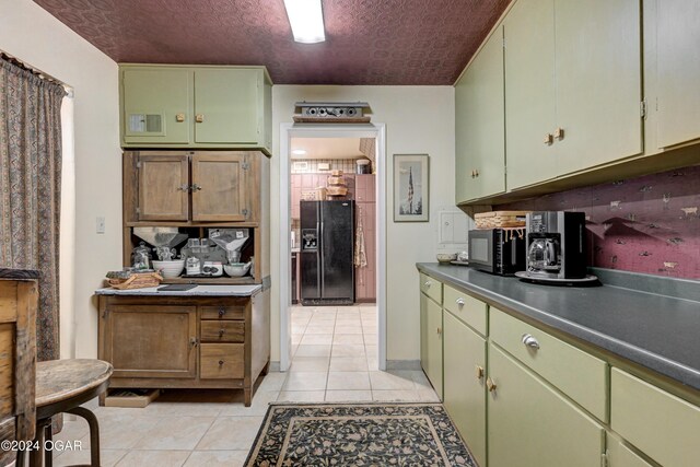114 W F St, Joplin, MO 64801 - kitchen featuring black appliances, green cabinets, light tile patterned floors, and dark countertops