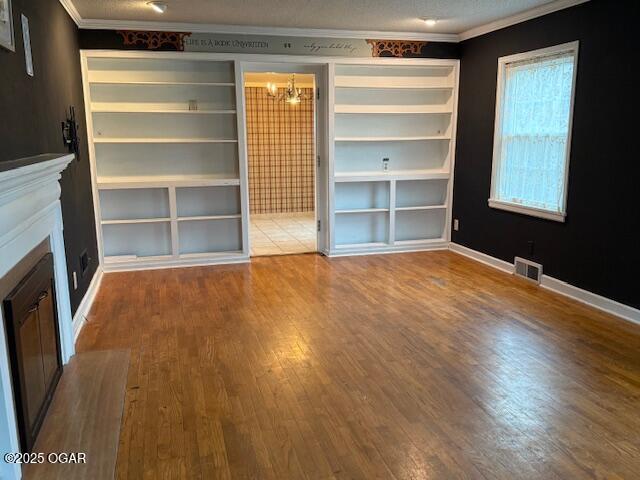 interior space with ornamental molding, wood finished floors, visible vents, and baseboards