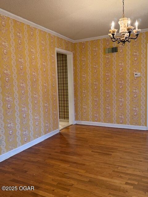 unfurnished room with baseboards, wallpapered walls, wood finished floors, and crown molding