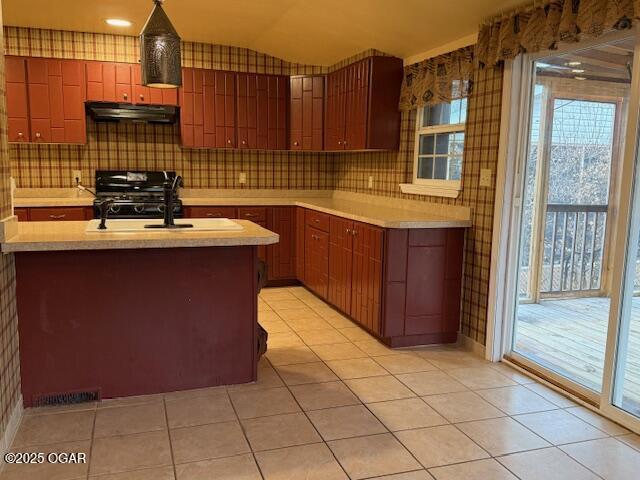 kitchen with under cabinet range hood, vaulted ceiling, light countertops, range, and tasteful backsplash