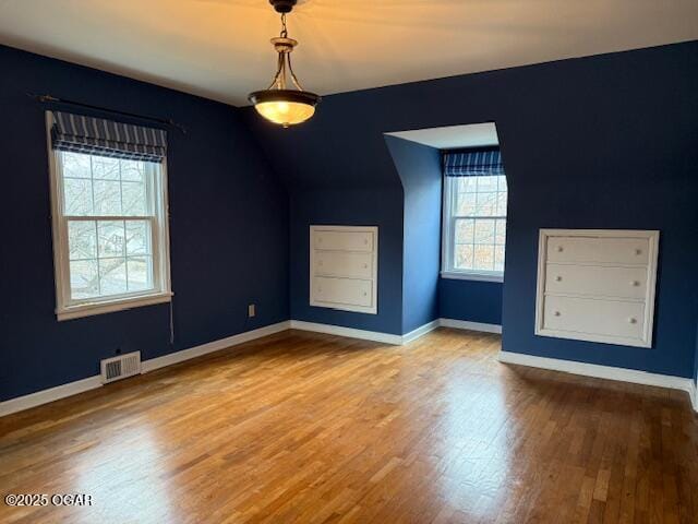 additional living space featuring wood finished floors, visible vents, and baseboards