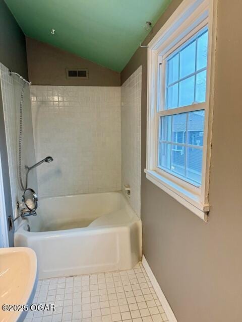 bathroom featuring lofted ceiling, visible vents, shower / tub combination, baseboards, and tile patterned floors