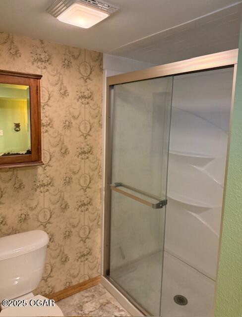 bathroom with a stall shower and wallpapered walls