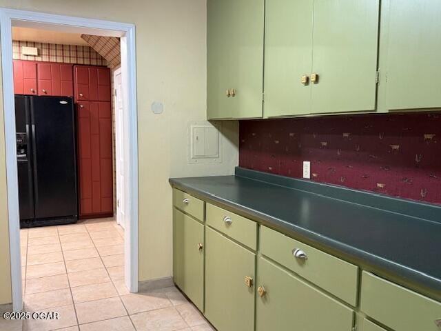 kitchen featuring dark countertops, black fridge, and light tile patterned flooring