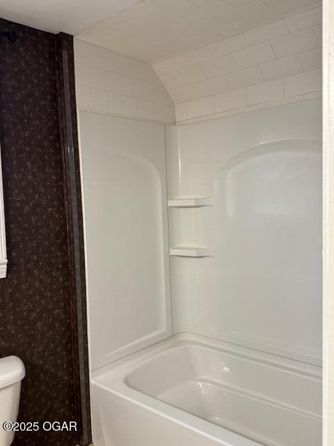 full bathroom with toilet, wallpapered walls, and washtub / shower combination