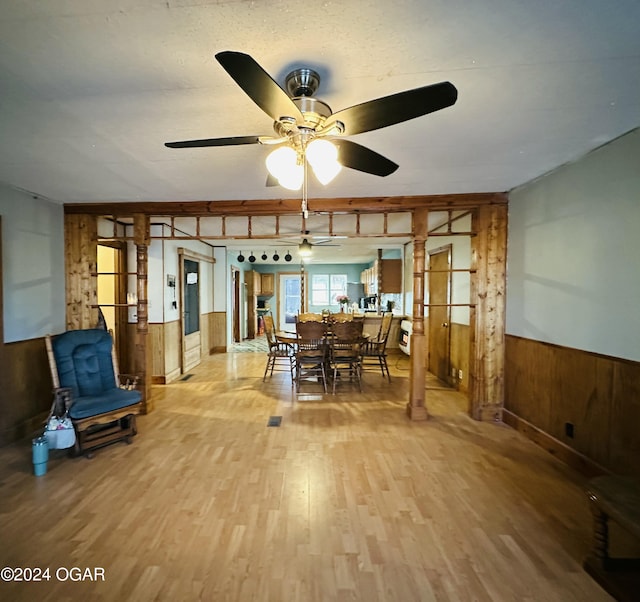 dining space featuring ceiling fan, hardwood / wood-style floors, a textured ceiling, and wooden walls