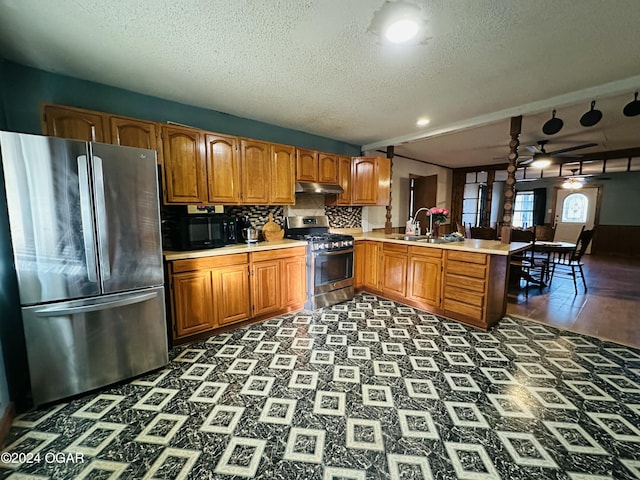 kitchen featuring sink, decorative backsplash, ceiling fan, appliances with stainless steel finishes, and kitchen peninsula