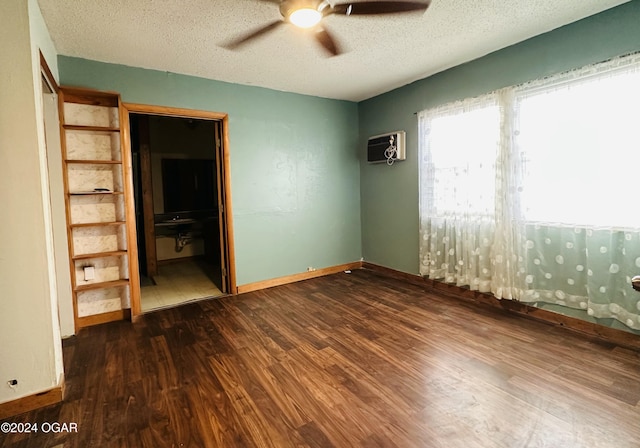 unfurnished bedroom featuring a wall mounted air conditioner, ceiling fan, dark hardwood / wood-style flooring, and a textured ceiling