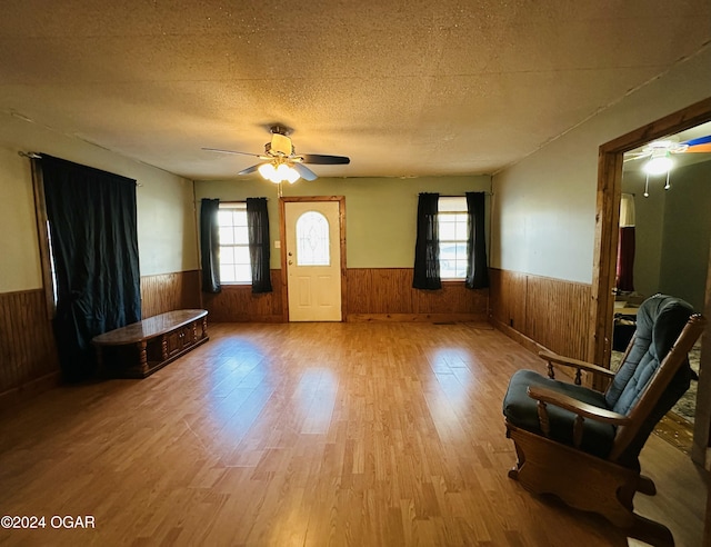 unfurnished room featuring a healthy amount of sunlight, a textured ceiling, wooden walls, and light hardwood / wood-style flooring