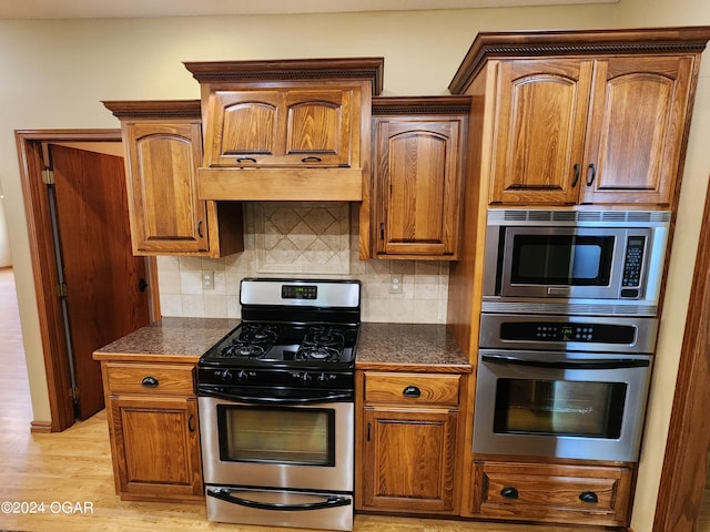 kitchen featuring decorative backsplash, appliances with stainless steel finishes, and light hardwood / wood-style flooring