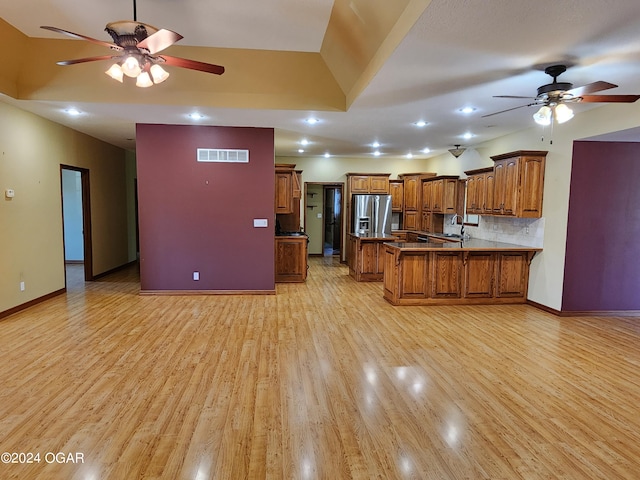 kitchen with kitchen peninsula, ceiling fan, stainless steel fridge with ice dispenser, decorative backsplash, and light hardwood / wood-style flooring