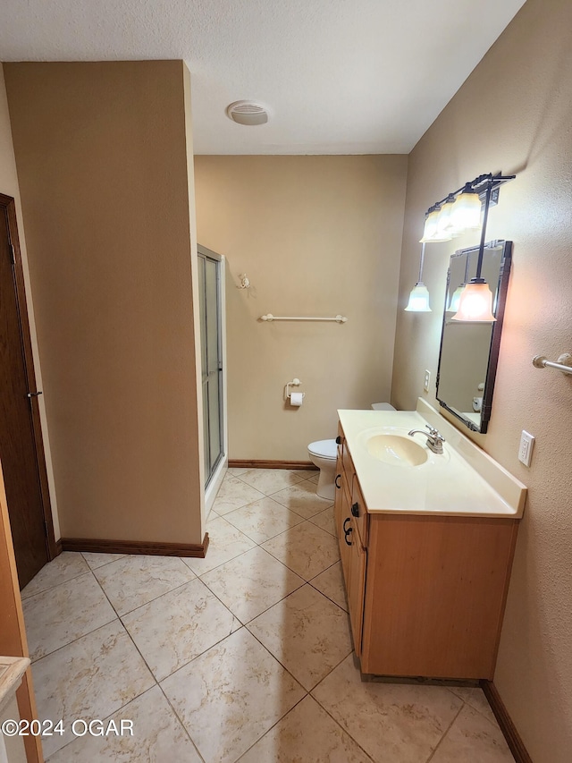 bathroom featuring vanity, toilet, tile patterned floors, and a shower with shower door