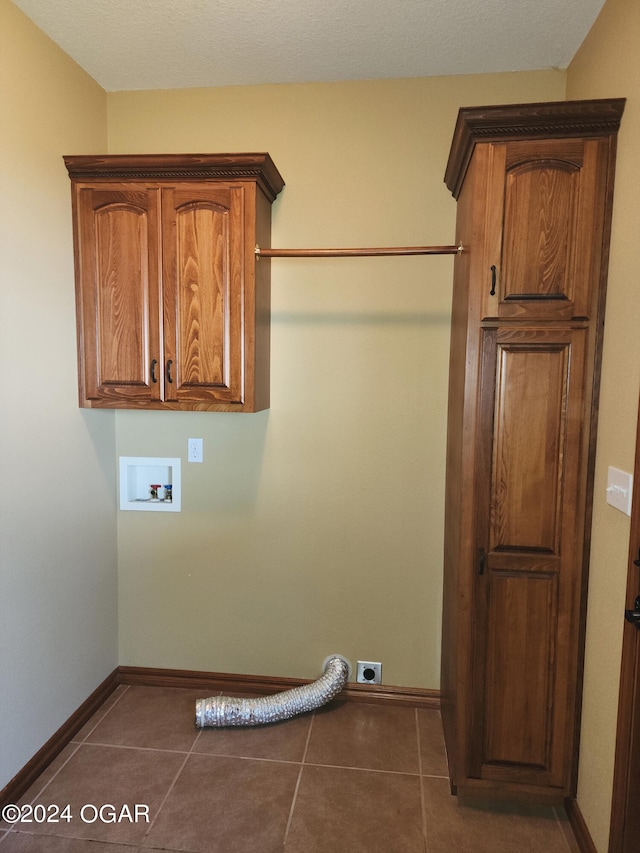 washroom featuring cabinets, hookup for an electric dryer, dark tile patterned floors, and hookup for a washing machine