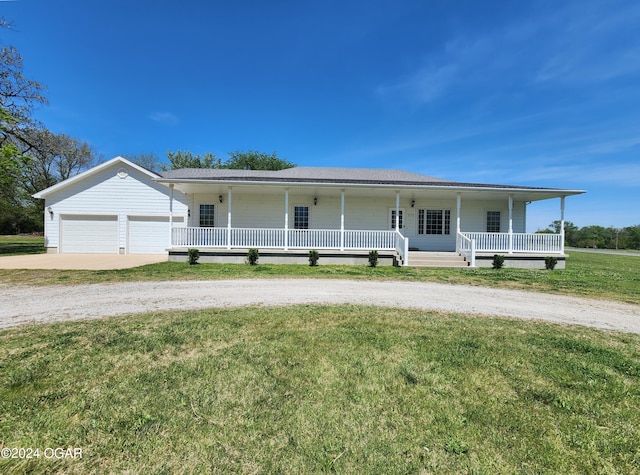 view of front of house with a front lawn, covered porch, a garage, and an outbuilding