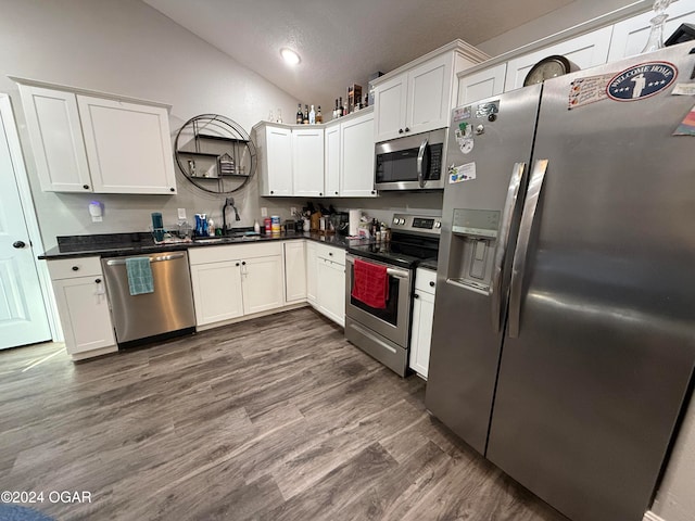 kitchen featuring stainless steel appliances, white cabinetry, a textured ceiling, dark wood-type flooring, and vaulted ceiling