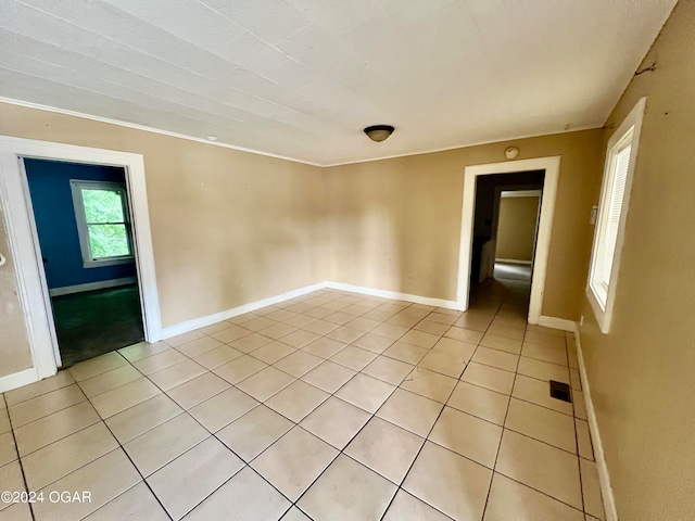 tiled spare room featuring ornamental molding