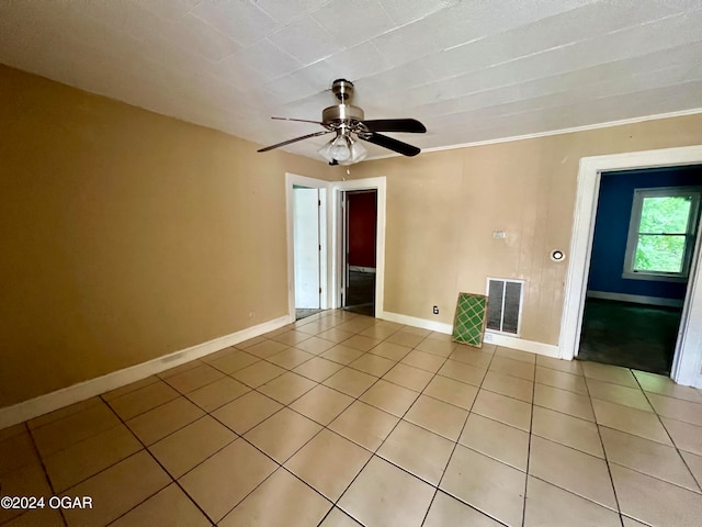 tiled empty room featuring ceiling fan and ornamental molding