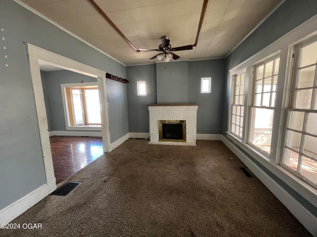 unfurnished living room with a fireplace, ceiling fan, crown molding, and carpet