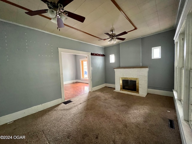 unfurnished living room featuring carpet, crown molding, a healthy amount of sunlight, and a brick fireplace