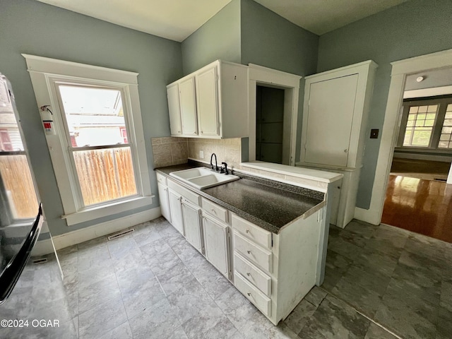 kitchen with white cabinets, sink, kitchen peninsula, and tasteful backsplash