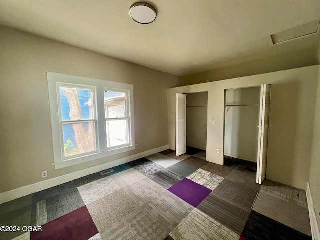 unfurnished bedroom with multiple closets and dark carpet