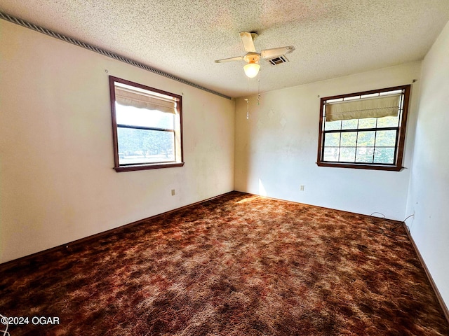 carpeted empty room featuring a textured ceiling, plenty of natural light, and ceiling fan