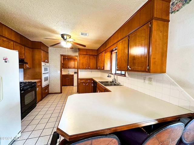 kitchen featuring backsplash, black appliances, sink, ceiling fan, and kitchen peninsula