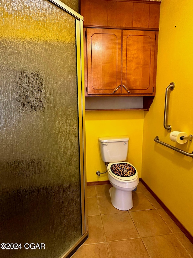 bathroom featuring tile patterned flooring, toilet, and a shower with door