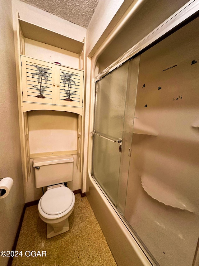 bathroom with shower / bath combination with glass door, a textured ceiling, and toilet